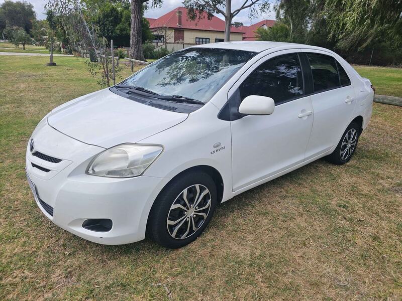 White Toyota Yaris sedan parked on grass